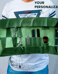 Green makeup organizer with tools held by a person wearing a white shirt with black splatter design.