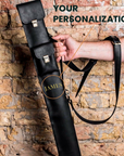 Black leather gun case with 'JAMES' branding held against a stone wall.