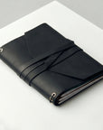 Black leather-bound notebook on a white surface