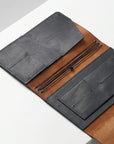 Open leather wallet with brown interior and gray exterior on a white surface