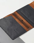 Two leather portfolios, one black and one brown, on a light gray surface.
