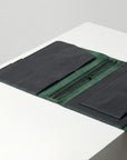 Green fabric with black leather accents on a white surface