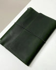 Green leather notebook with a string closure on a white surface