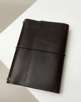 Dark brown leather notebook on a light beige and white background