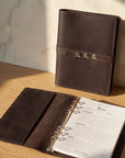 Brown leather planner on a wooden surface with sunlight casting shadows