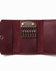 A round burgundy faux-suede crossbody bag with geometric paneling and a matching adjustable shoulder strap, displayed on a clean white background.