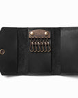 A black leather key ring case shown open on a white background, featuring a brass-toned metal key ring holder with six key rings and snap-button closure.