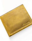 A mustard yellow leather bifold wallet with visible stitching and the brand name 'PIKORE' embossed on the bottom right, shown on a clean white background.