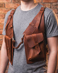 Person wearing a brown leather backpack against a brick wall.