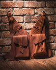 Two brown leather bags against a brick wall.