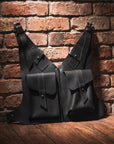 Two black leather bags against a brick wall.