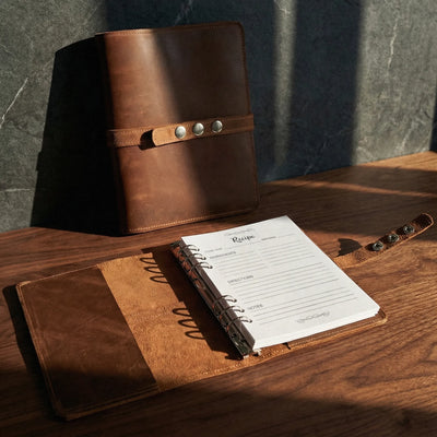 Brown leather notebook with a strap on a wooden surface
