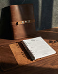 Brown leather notebook with a strap on a wooden surface