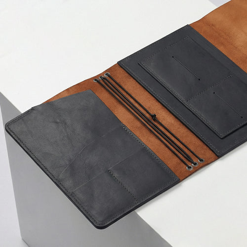 Two leather portfolios, one black and one brown, on a light gray surface.