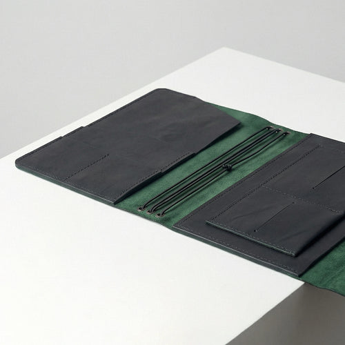 Green fabric with black leather accents on a white surface