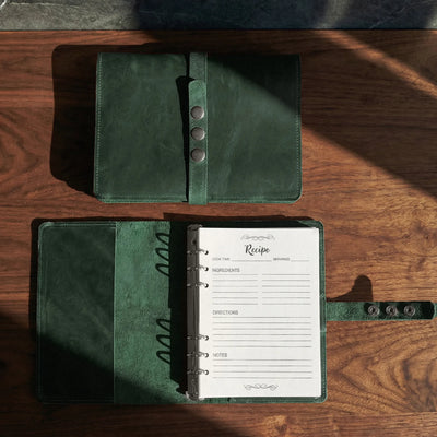 Green leather recipe book open on a wooden surface