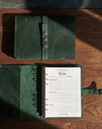 Green leather recipe book open on a wooden surface