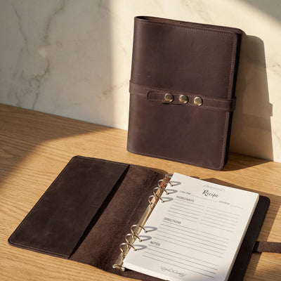 Brown leather planner on a wooden surface with sunlight casting shadows