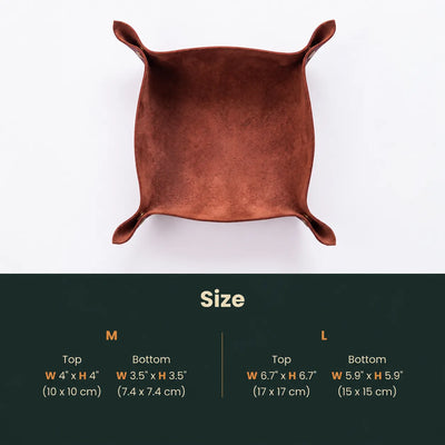 A square copper-colored leather tray with four raised corners, shown from above on a white background, with a dark green size chart below detailing measurements for M and L sizes.