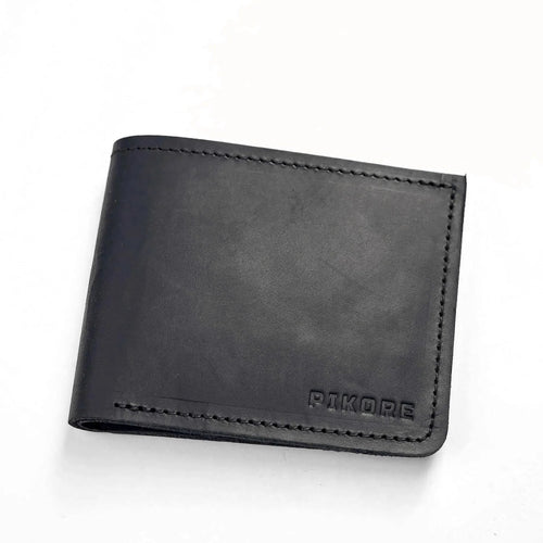 A black leather bifold wallet with visible stitching and the brand name 'PAKORE' debossed in the bottom right corner, shown on a plain white background.
