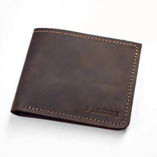 A dark brown leather bi-fold wallet with visible stitching and the brand name 'PIKORE' embossed in the bottom right corner, shown on a plain white background.
