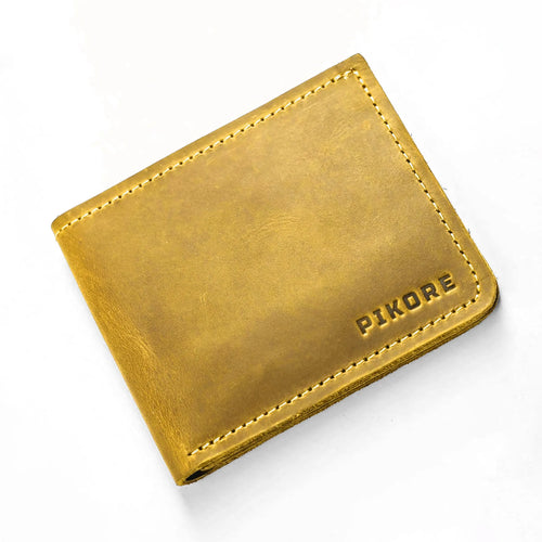 A mustard yellow leather bifold wallet with visible stitching and the brand name 'PIKORE' embossed on the bottom right, shown on a clean white background.