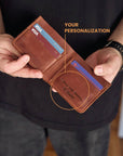 Person holding a brown leather wallet with personalized engraving, showing Visa cards inside.
