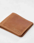 A brown leather bifold wallet with 'PIKORE' debossed on the front, shown on a clean white background.