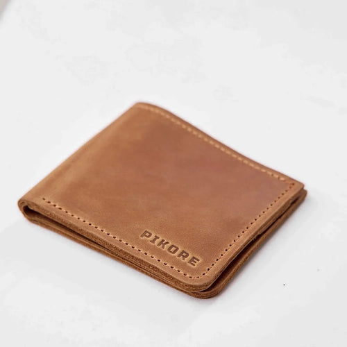 A brown leather bifold wallet with 'PIKORE' debossed on the front, shown on a clean white background.