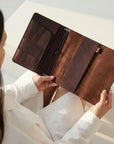 Person holding a brown leather portfolio against a neutral background