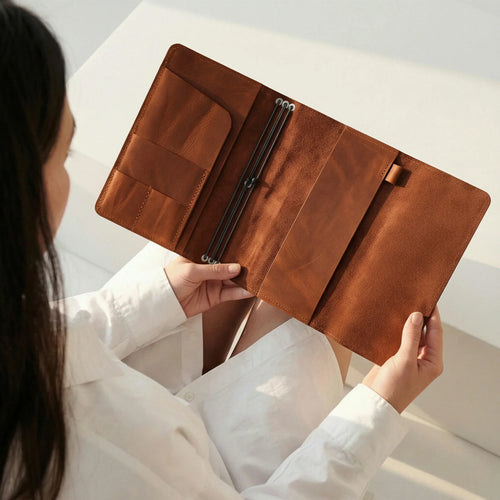 Person holding a brown leather wallet against a neutral background
