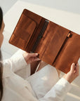 Person holding a brown leather wallet against a neutral background