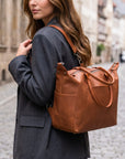 Woman carrying a brown leather bag on a city street