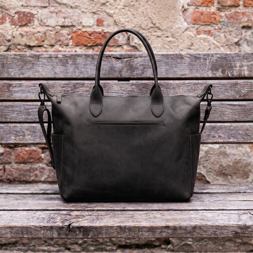 Black leather bag on a wooden surface with a brick wall background