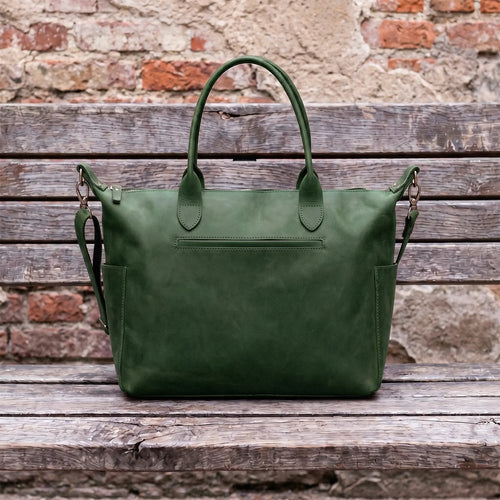 Green leather bag on a wooden surface with a brick wall background