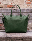 Green leather bag on a wooden surface with a brick wall background