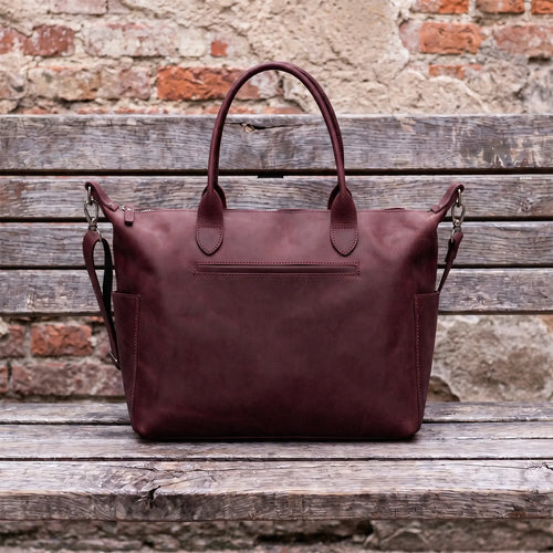 Brown leather bag on a wooden surface with a brick wall background