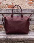 Brown leather bag on a wooden surface with a brick wall background