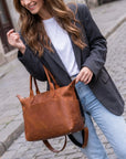 Woman holding a brown leather bag on a cobblestone street