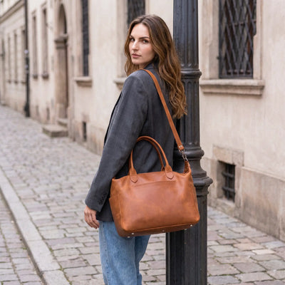 Woman holding a brown leather handbag on a city street.