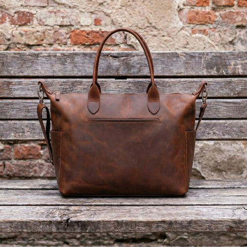 Brown leather bag on a wooden surface with a rustic brick wall background