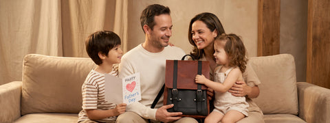 Family of four sitting on a couch with a woman holding a handbag and a child holding a card.