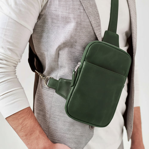 Green crossbody bag worn by a person on a plain background