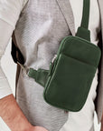 Green crossbody bag worn by a person on a plain background