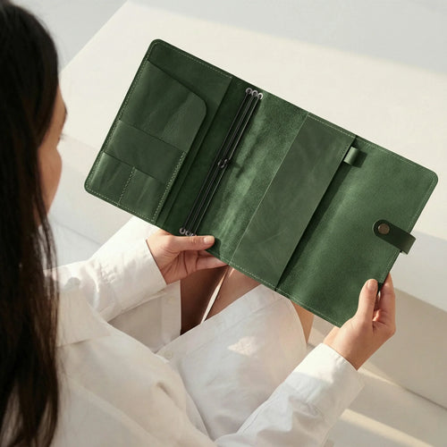 Person holding a green leather wallet against a neutral background