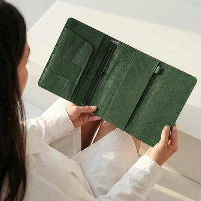 Person holding a green wallet with a neutral background