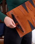 Person holding a brown leather clutch with geometric patterns