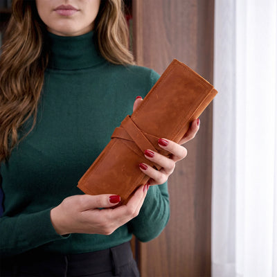 Woman holding a brown leather wallet against a neutral background