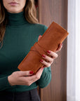 Woman holding a brown leather wallet against a neutral background