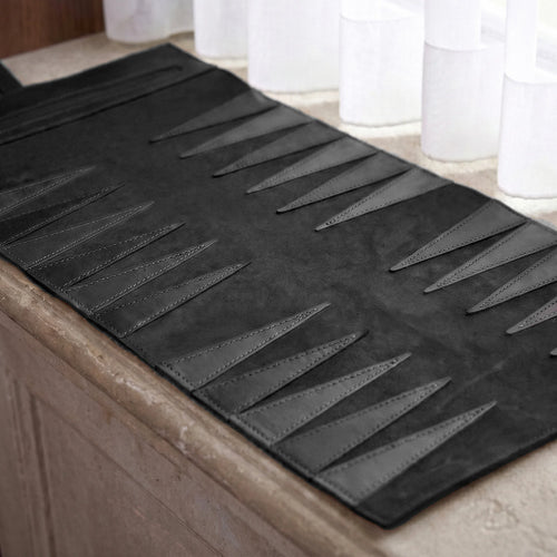 Black bath mat with geometric pattern on a bathroom floor.